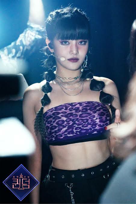 Yoon Minnie stood mere inches from Y/N, wearing a deep purple robe curled around her slender body and her hair tied in a high ponytail